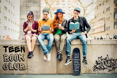 four teenager hanging out on a graffitied wall reading